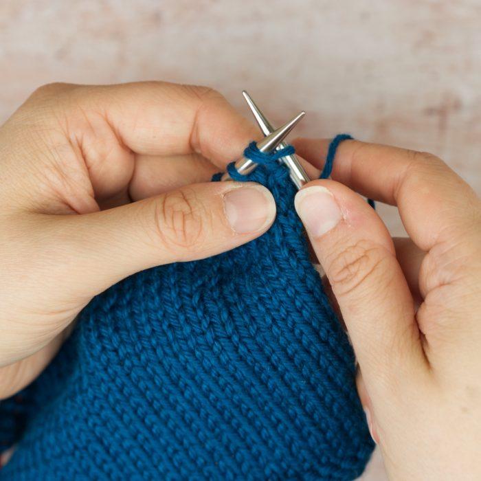 hands hold blue knitting