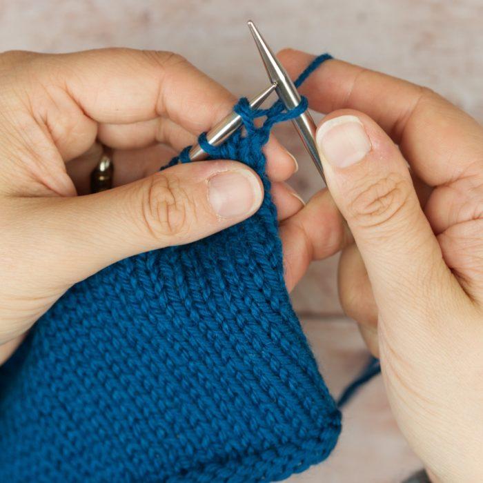 hands hold blue knitting