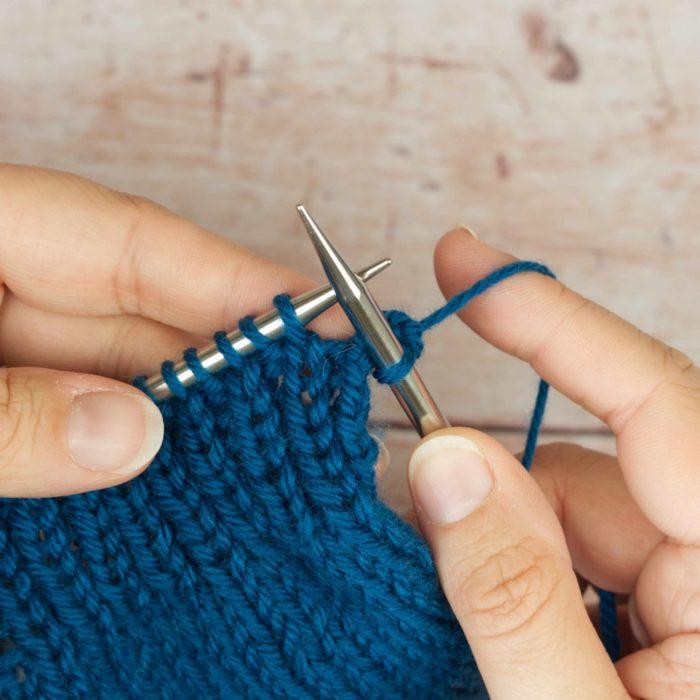 hands holding mid blue knitting