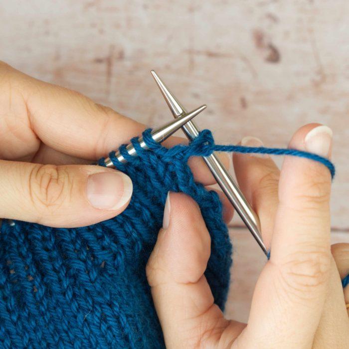 hands holding mid blue knitting ready to purl