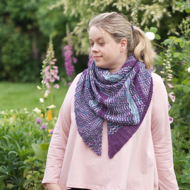 seafoam and purple lace and garter shawl worn bandana style by woman in a pink top