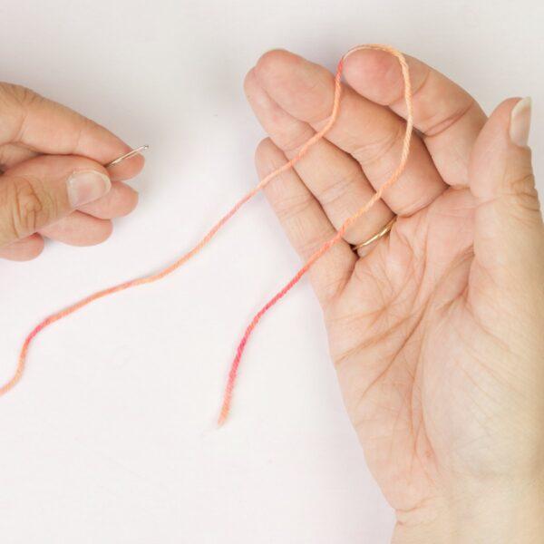 hands holding yarn yarn and a threading a needle