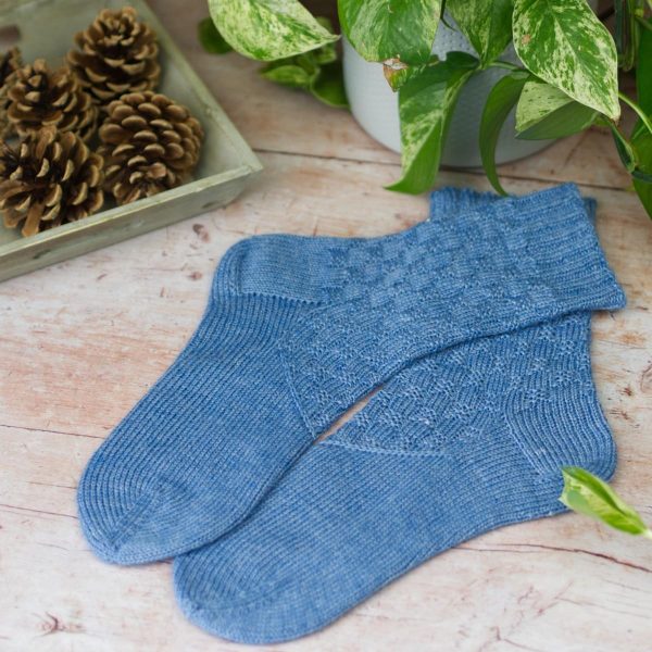 laying on a table mid blue texture sock with diagonal band across arch