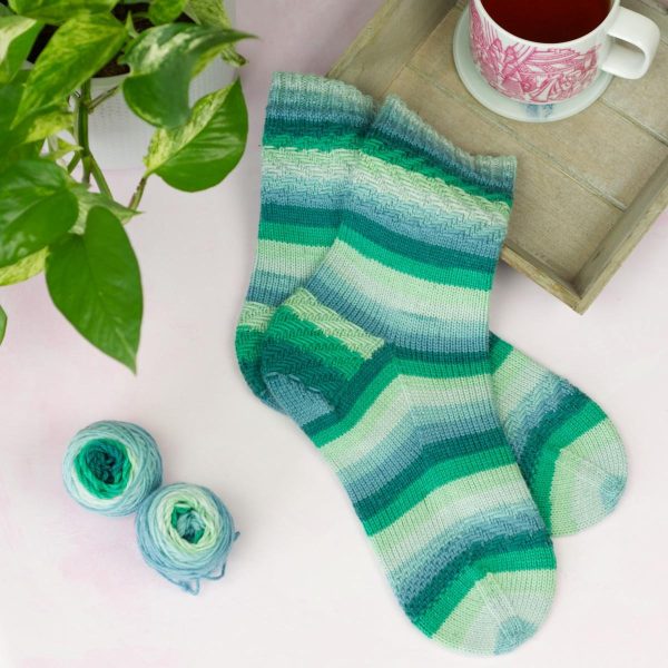 laying flat on a table sea green striped socks with woven texutre at cuff, heel and ball of foot
